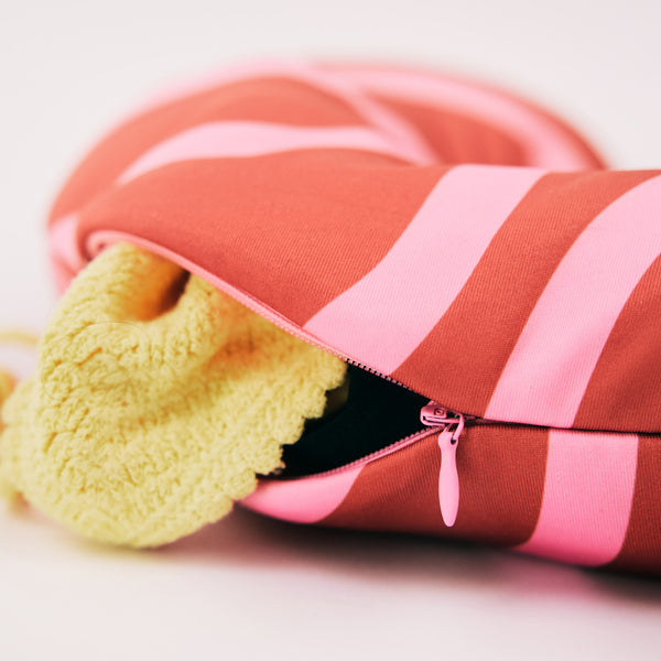 Red and pink striped travel pillow with a zipper, stuffed with a yellow towel
